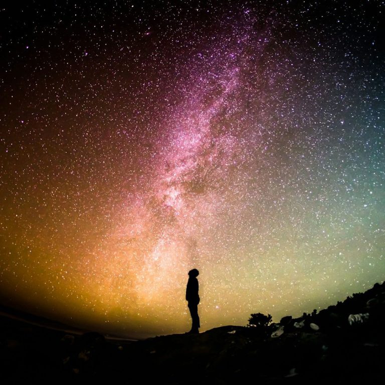 Silhouette of a person pondering life under the stars and Milky Way.